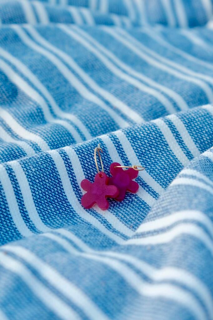 Costa Brava in Bloom — Hibiscus Amarillo handcrafted earrings styled on natural fabrics, highlighting Mediterranean-inspired tones and shapes.

